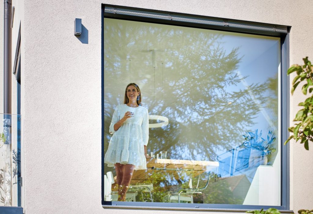 Nachhaltige Fenster Augsburg – Bewohnerin am modernen Neubau Fenster mit hoher Energieeffizienz